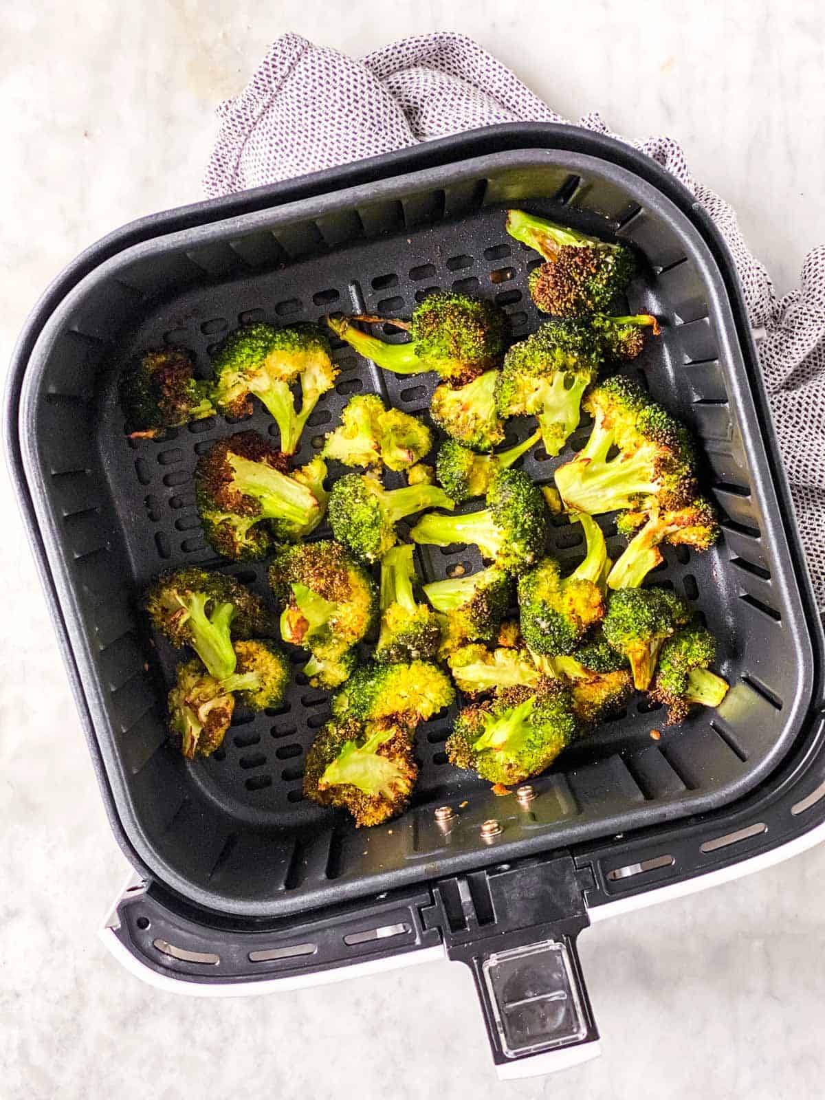 air fryer basket with roasted broccoli florets inside