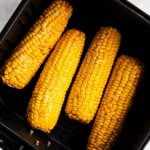 four cooked ears of corn in air fryer basket