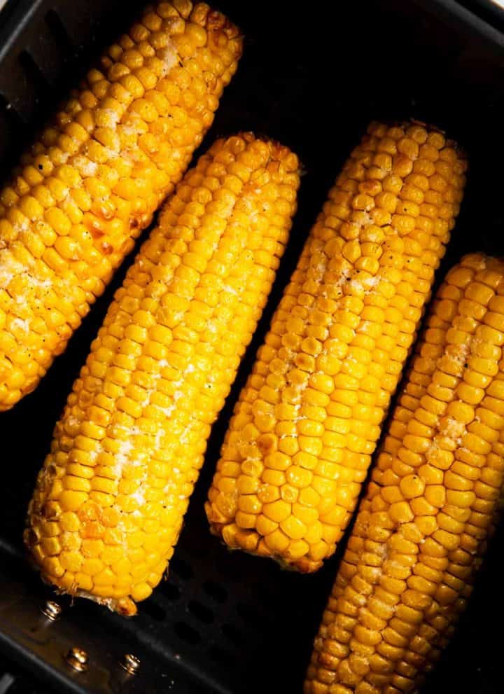 four cooked ears of corn in air fryer basket