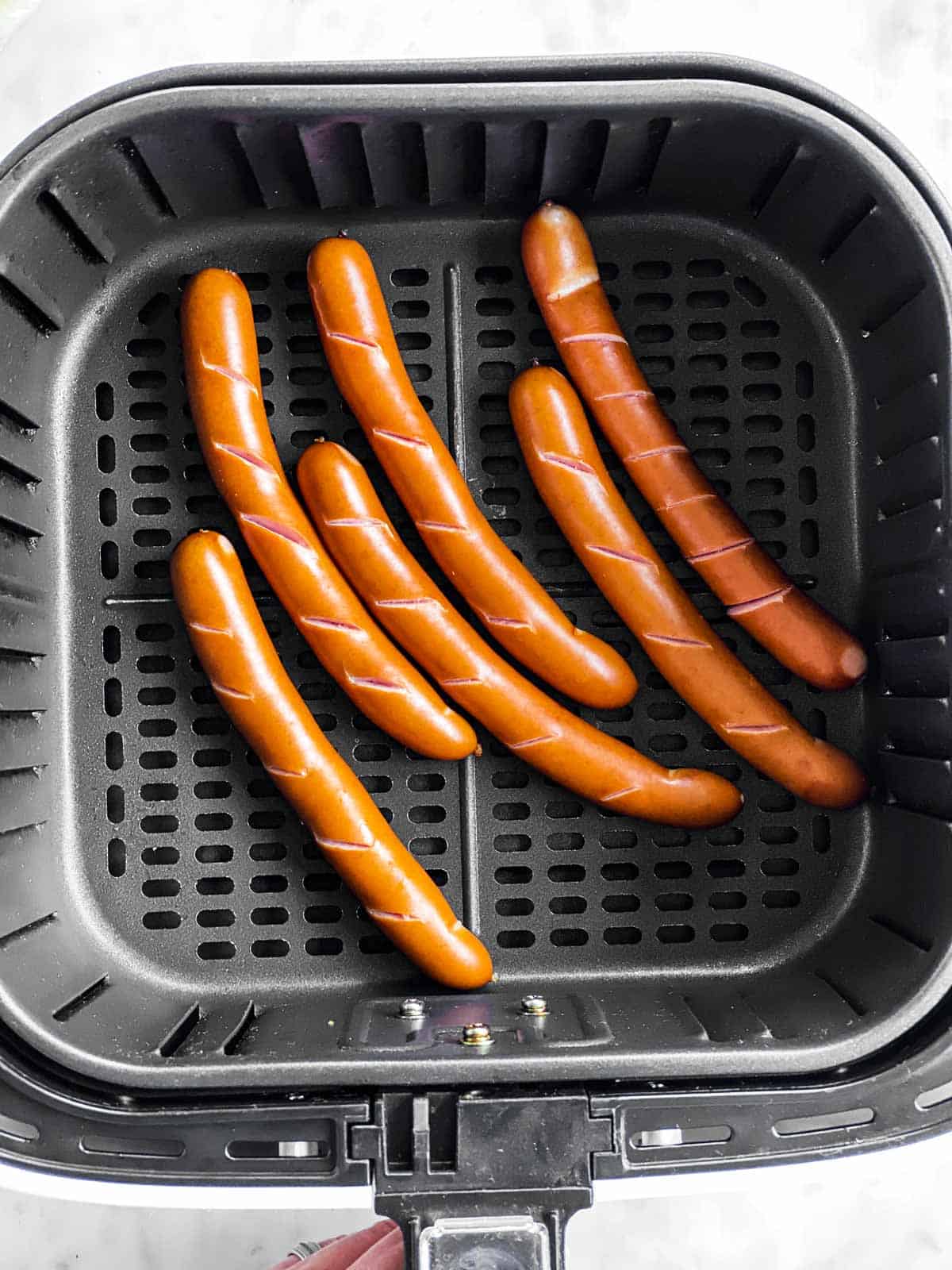 six cooked hot dogs in air fryer basket