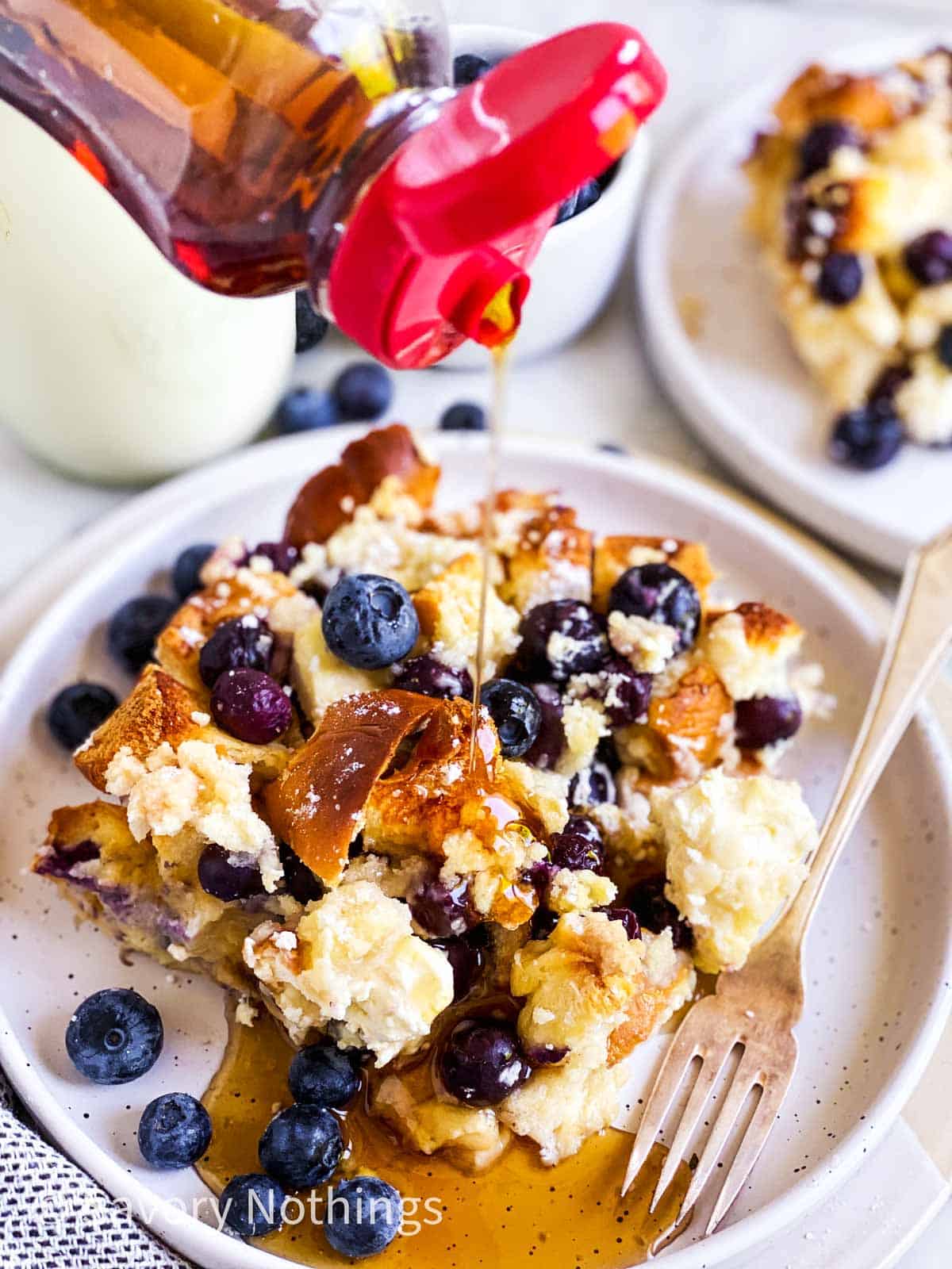 syrup pouring over blueberry French toast casserole on a white plate