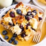 slice of blueberry French toast casserole with maple syrup on white plate