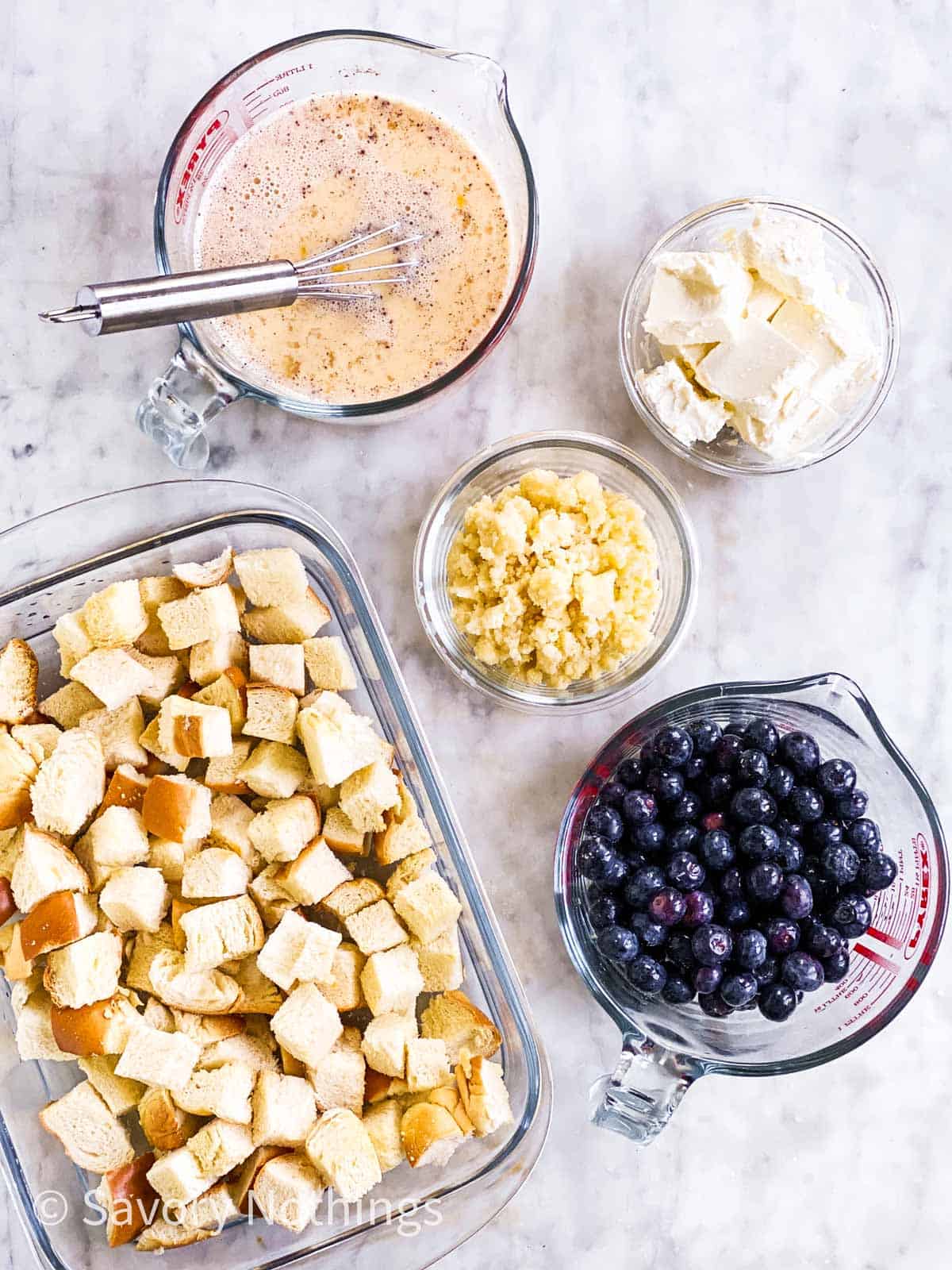 prepared ingredients for a blueberry French toast casserole on a white marble surface