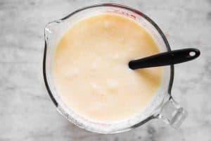 wet ingredients for buttermilk pancakes and glass bowl with rubber spatula