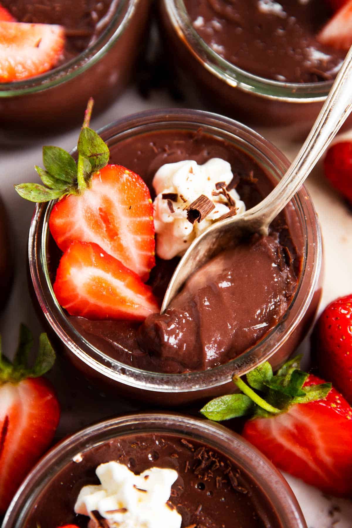 jar of homemade chocolate pudding with strawberries, spoon stuck in pudding