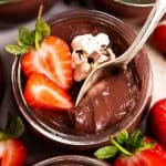 jar of homemade chocolate pudding with strawberries, spoon stuck in pudding