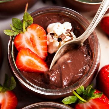 jar of homemade chocolate pudding with strawberries, spoon stuck in pudding