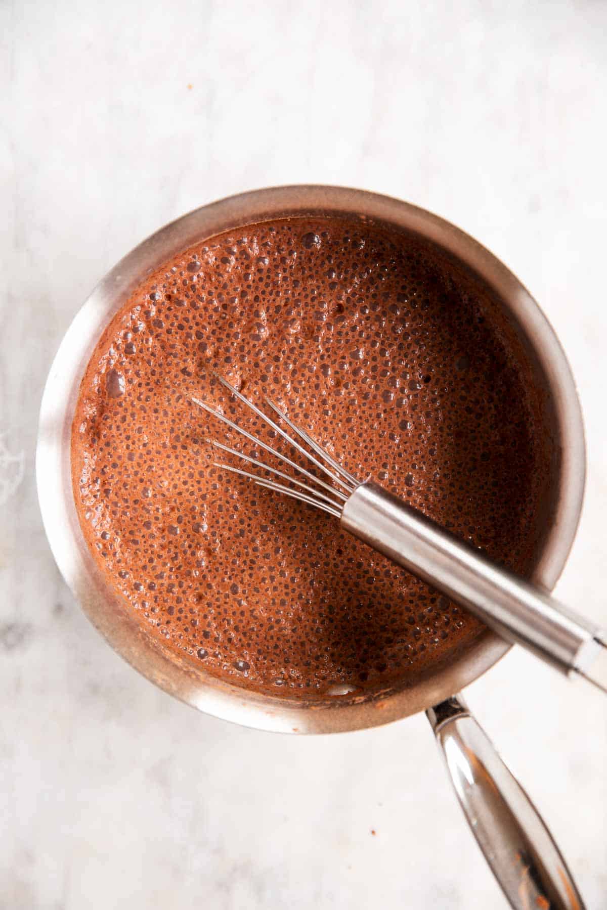 whisked mixture for homemade chocolate pudding in saucepan with wire whisk