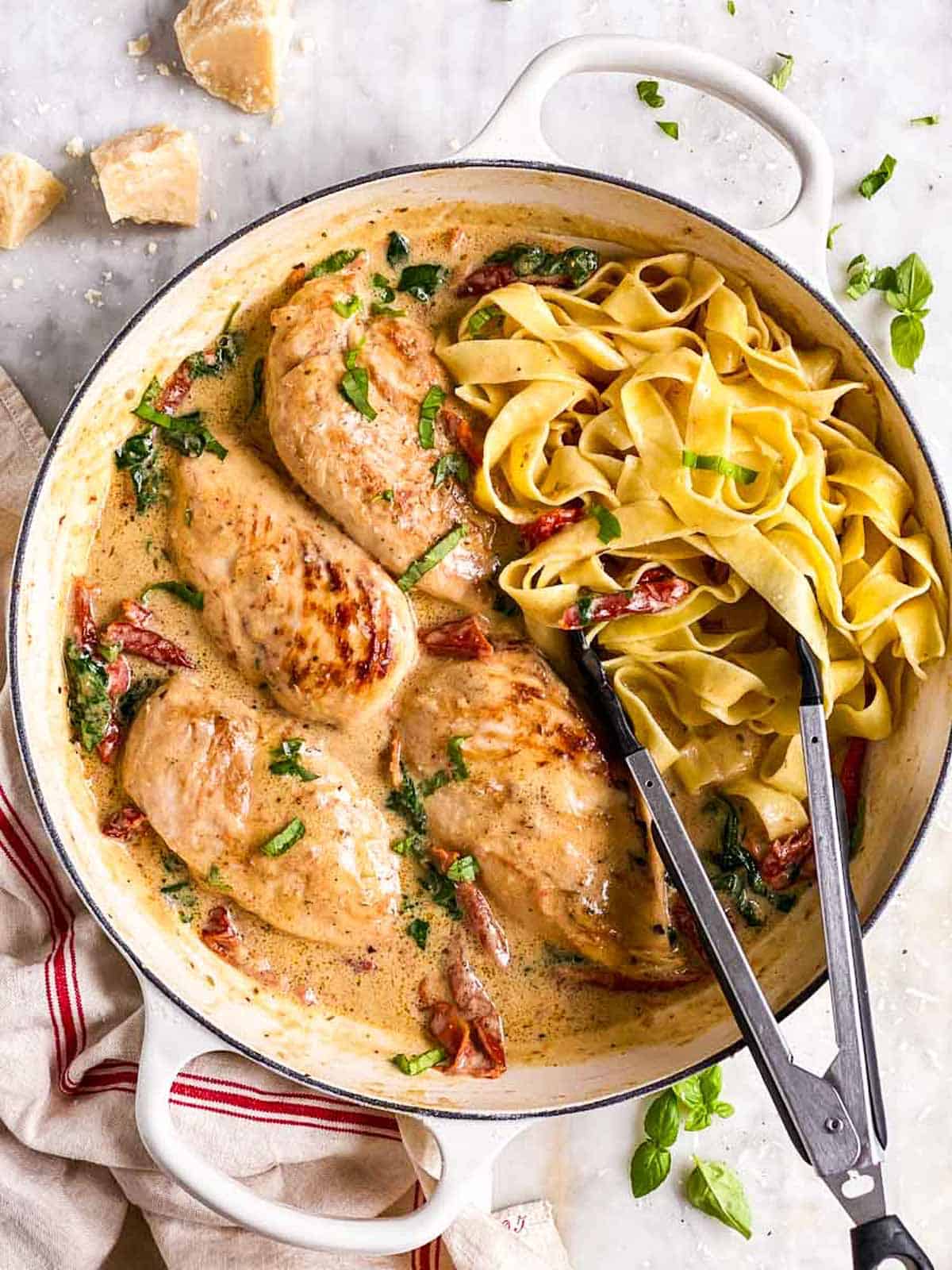 overhead view of tuscan chicken in white cast iron skillet with pasta