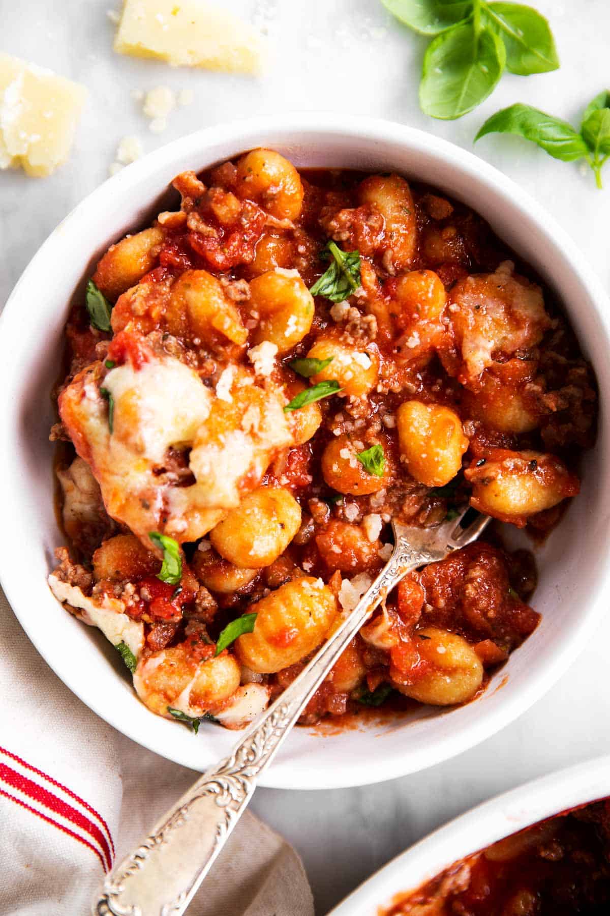 overhead view of gnocchi with meat sauce in white bowl with fork