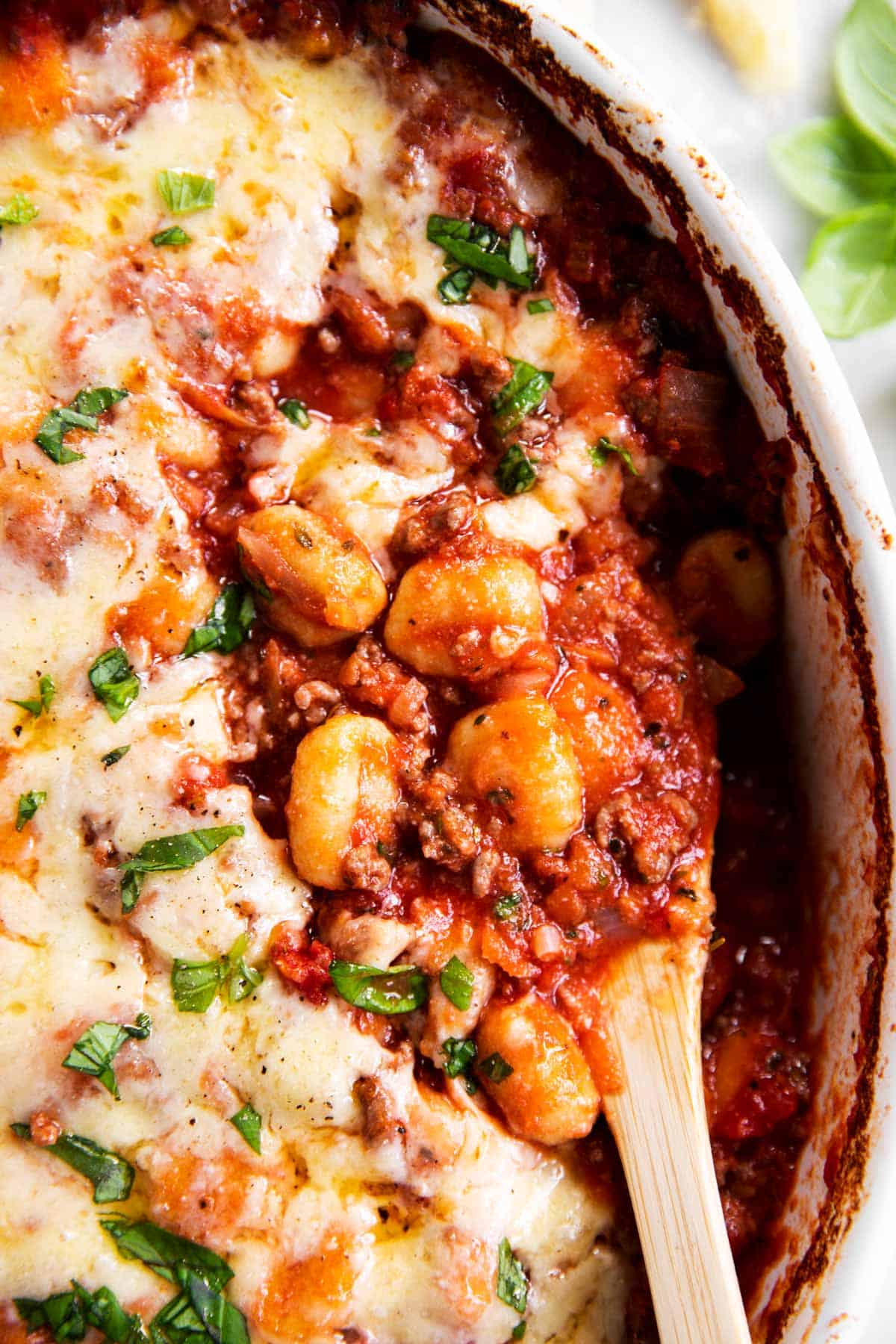 close up photo of wooden spoon stuck in gnocchi bake