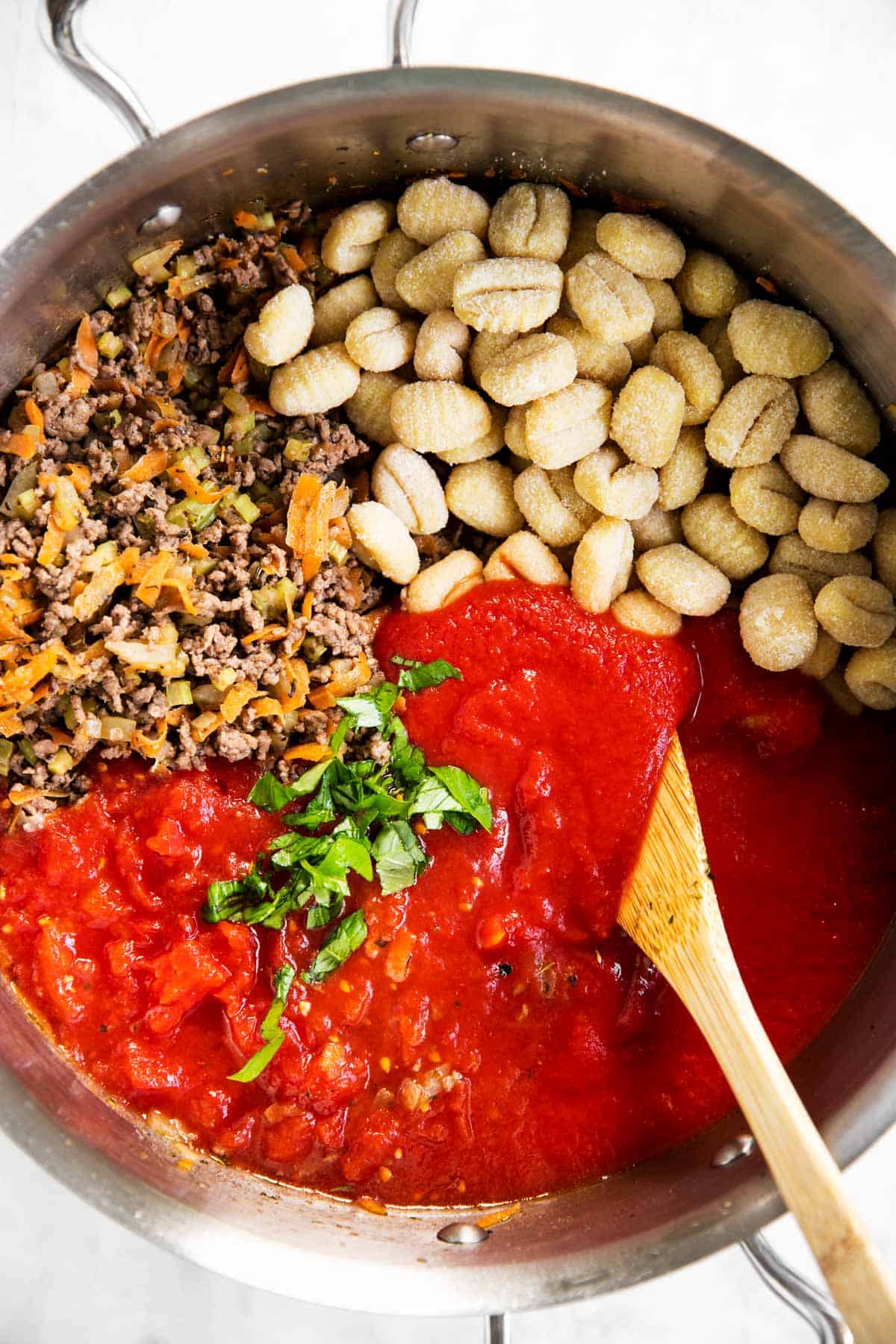 cooked ground beef and vegetable mixture in skillet with tomato sauce and plain gnocchi