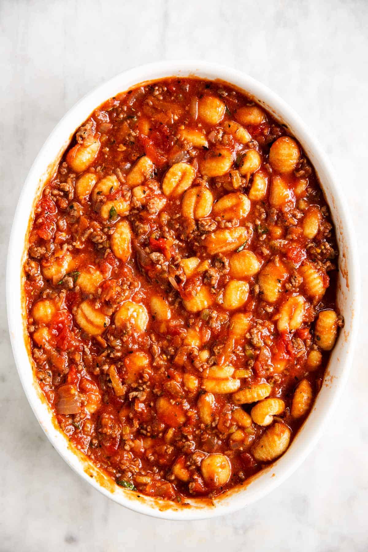 gnocchi, ground beef and tomato sauce mixture in white casserole dish