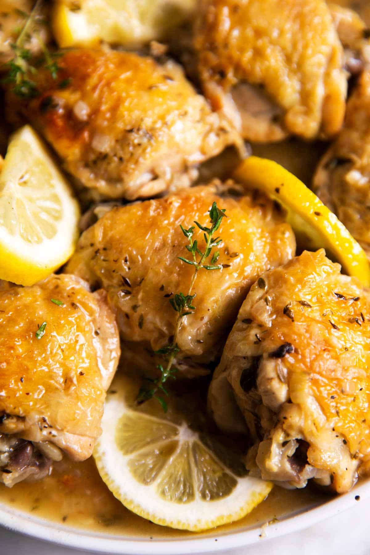 close up photo of lemon chicken thighs on plate with lemon slices