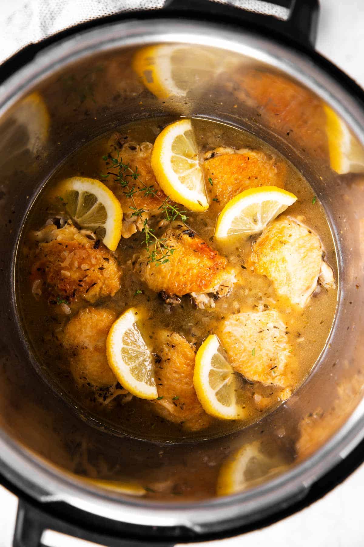 overhead view of lemon chicken thighs in instant pot with lemon slices