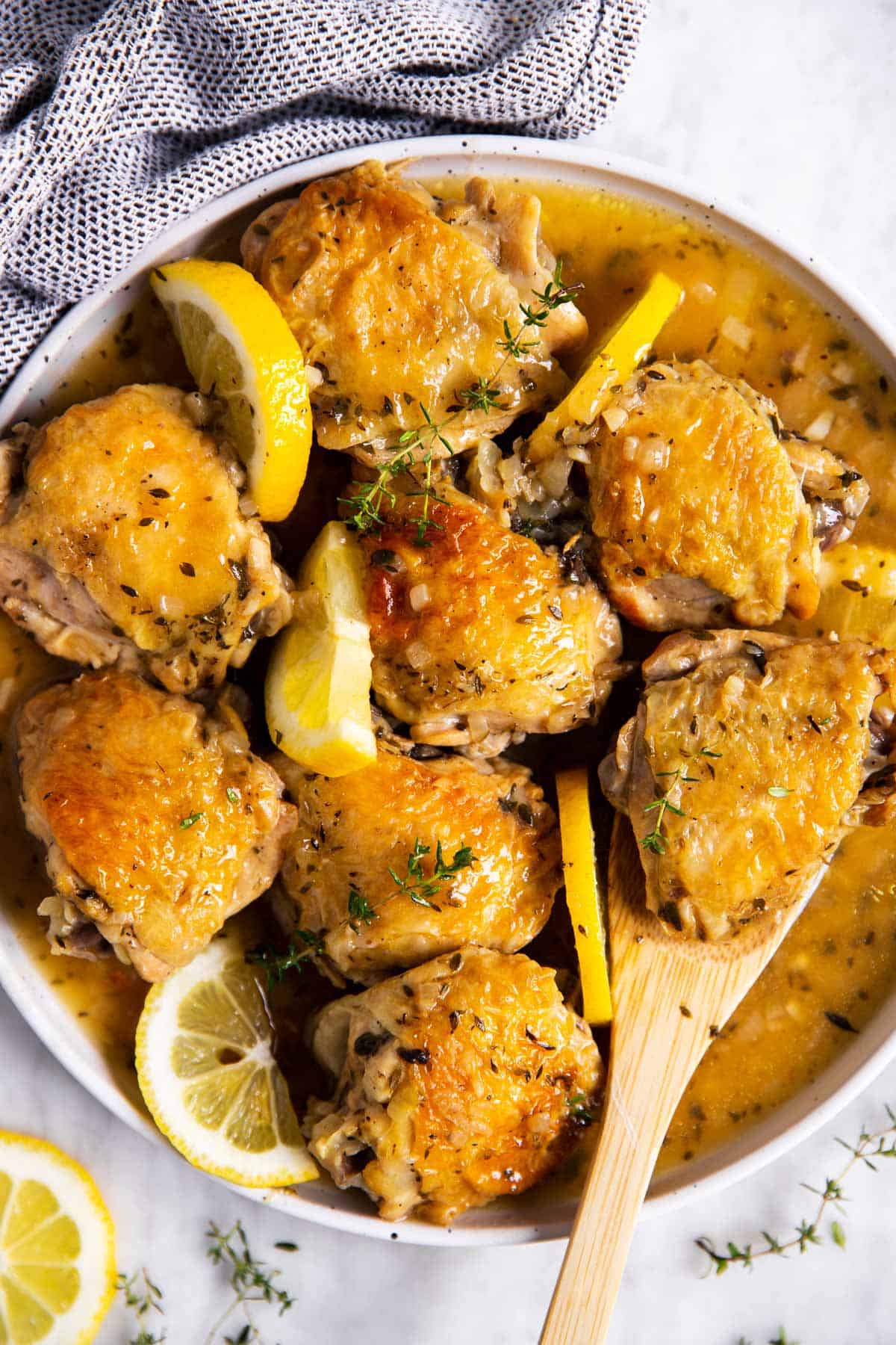 overhead view of instant pot lemon chicken on white plate with wooden spoon