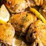 close up photo of lemon chicken thighs on plate with lemon slices