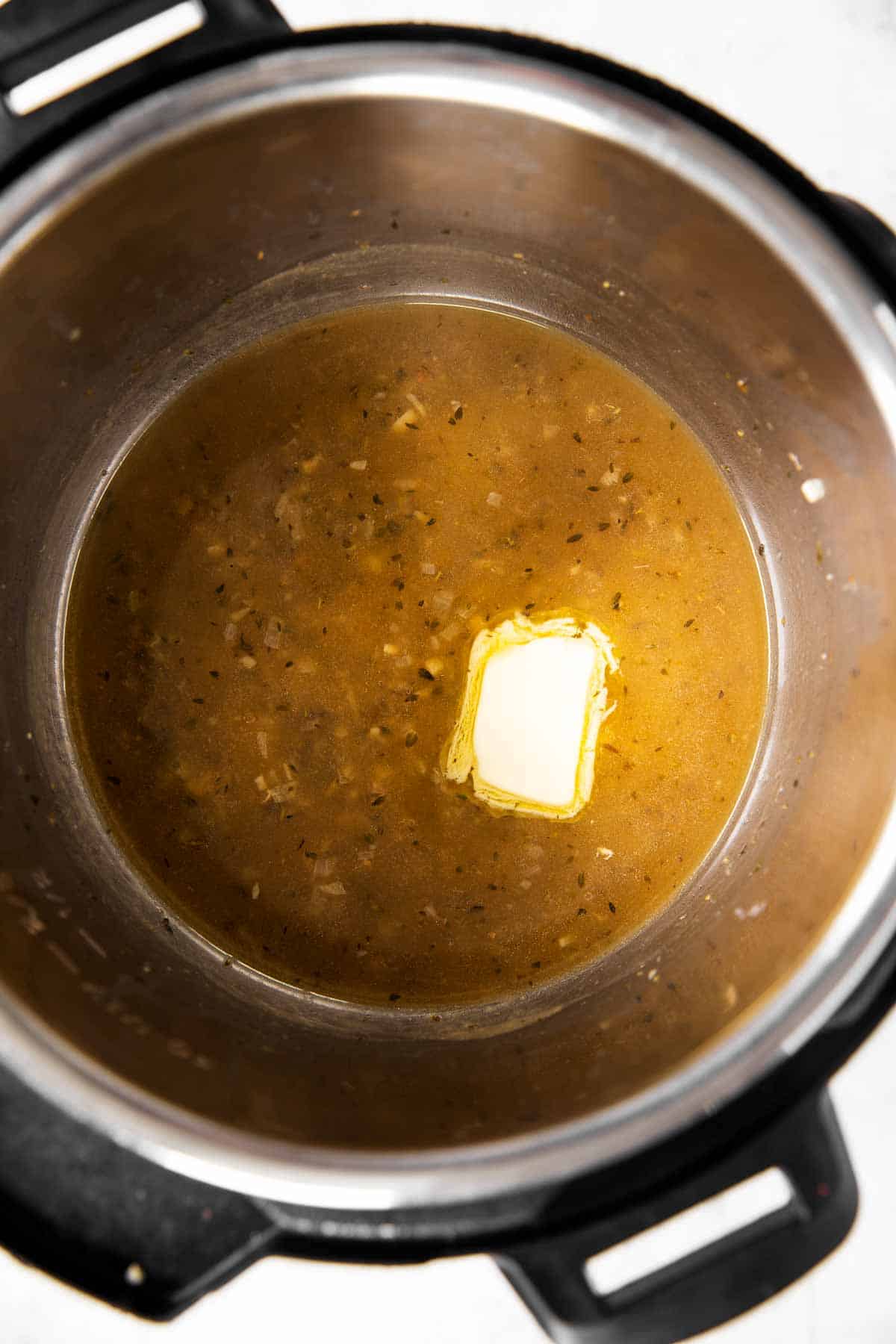 overhead view of instant pot with lemon sauce and pat of butter