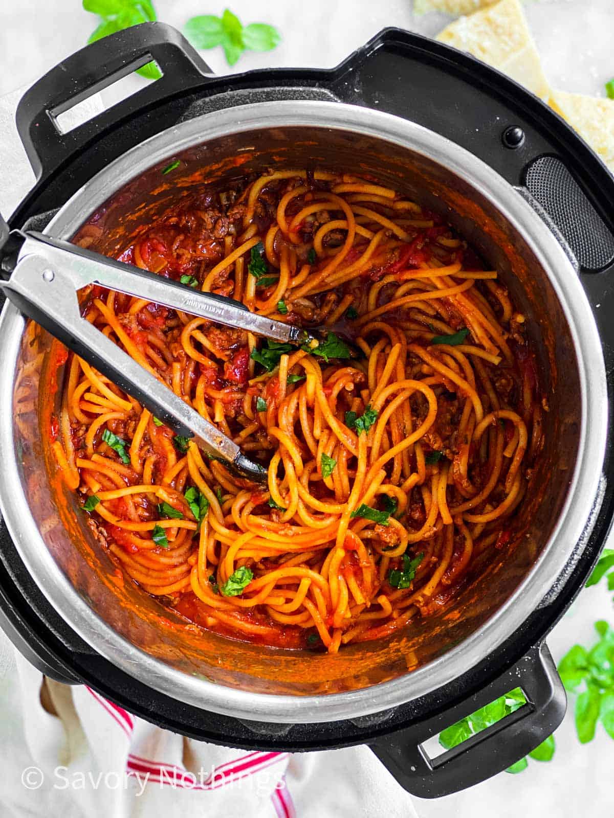 overhead view of instant pot filled with spaghetti and meat sauce with kitchen tongs stuck in
