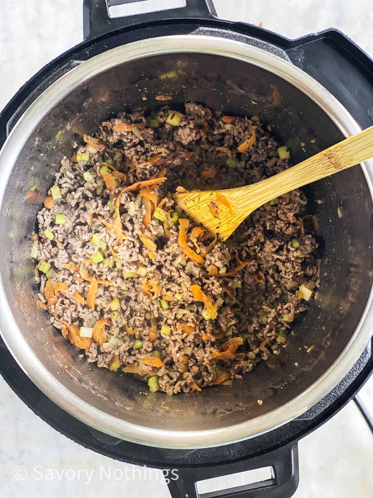sautéed vegetables and browned ground beef in instant pot with wooden spoon