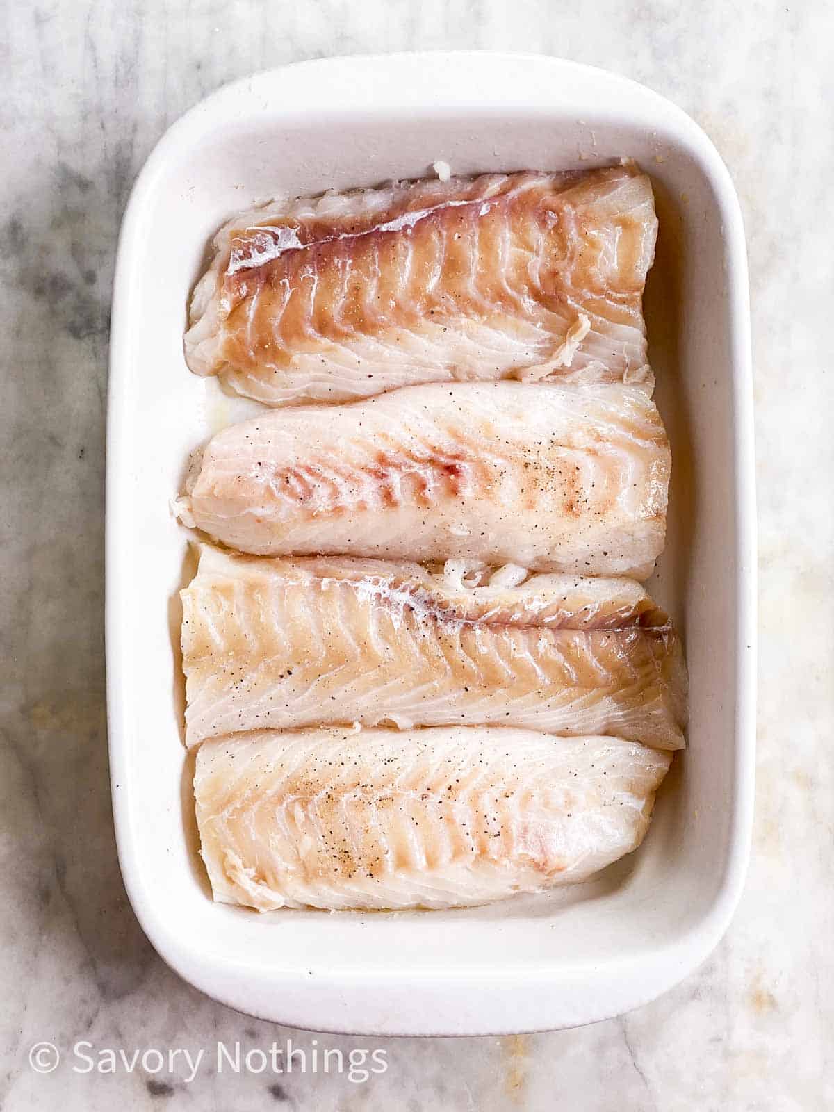 four cod loin fillets in white casserole dish