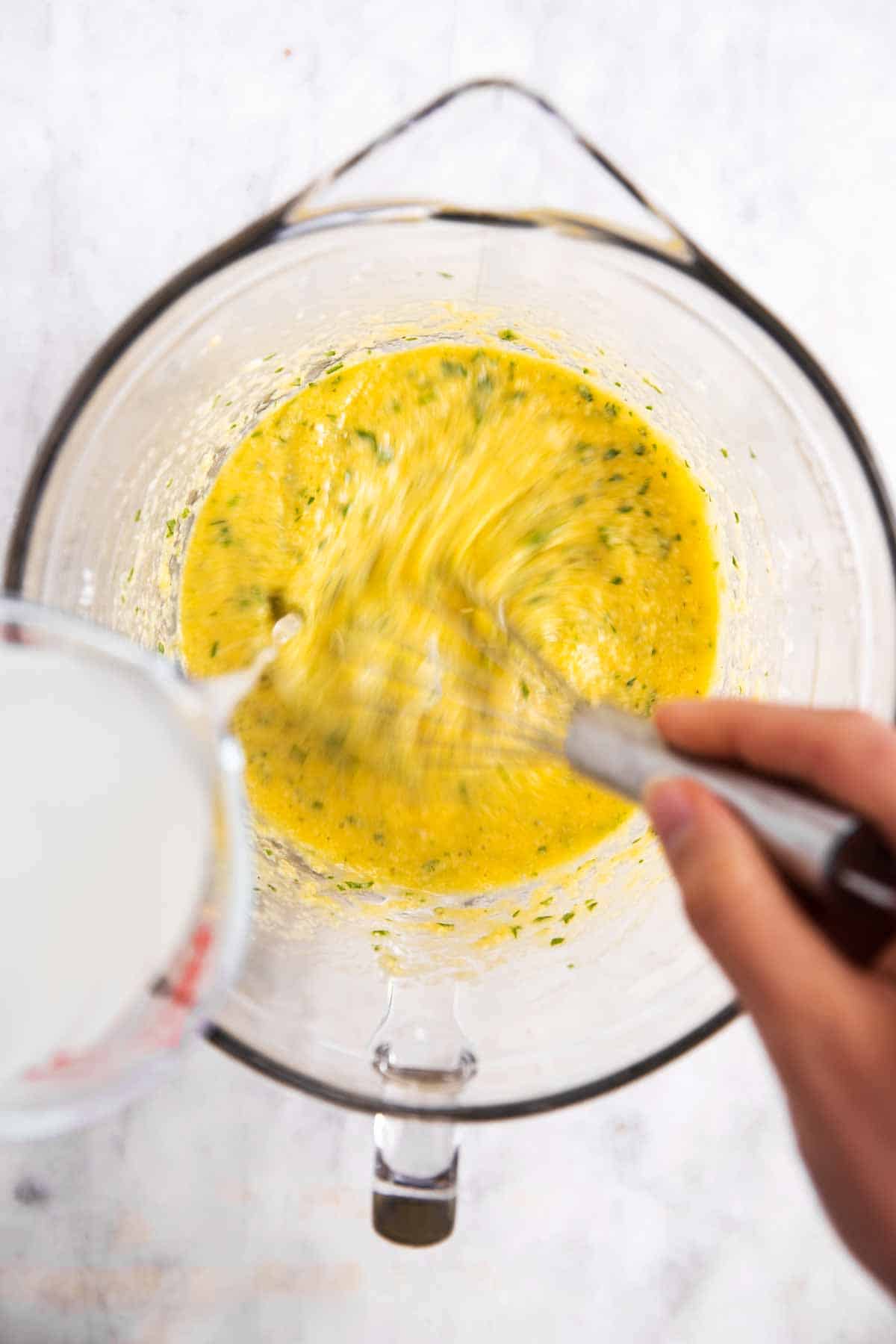 female hand whisking pasta cooking water into egg mixture in glass bowl
