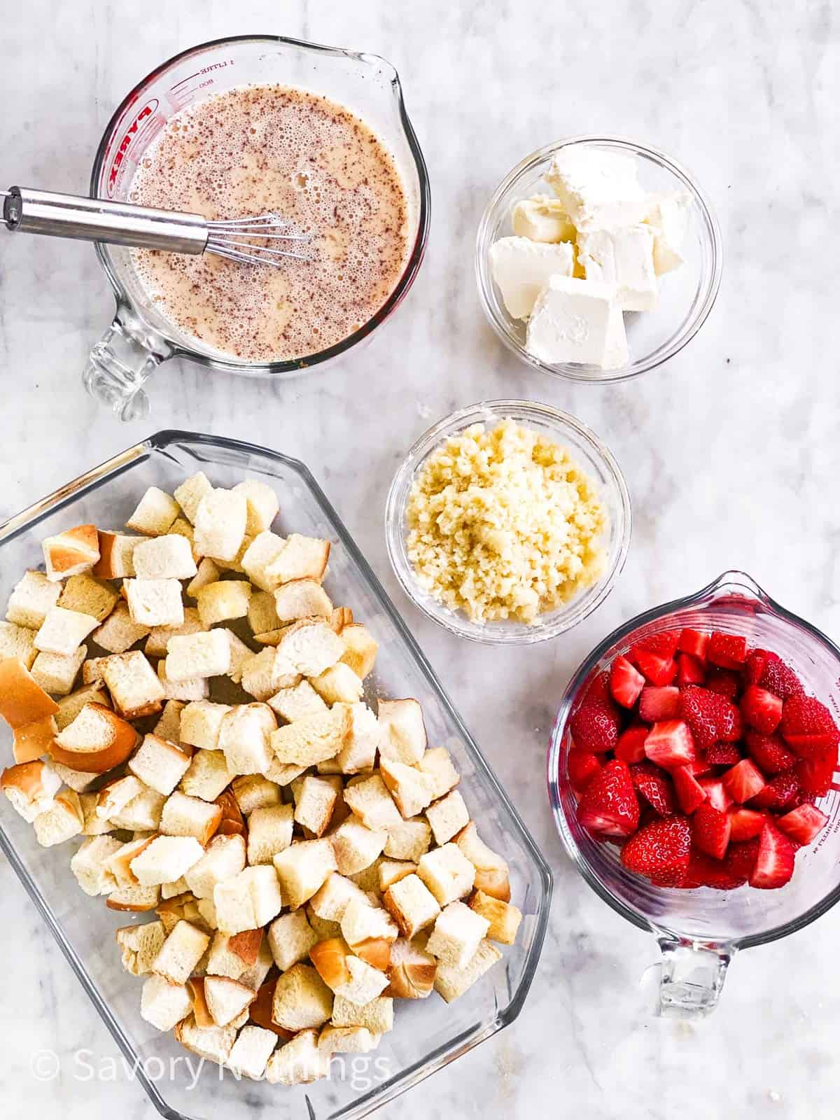 assembled ingredients for strawberry French toast casserole on marble surface