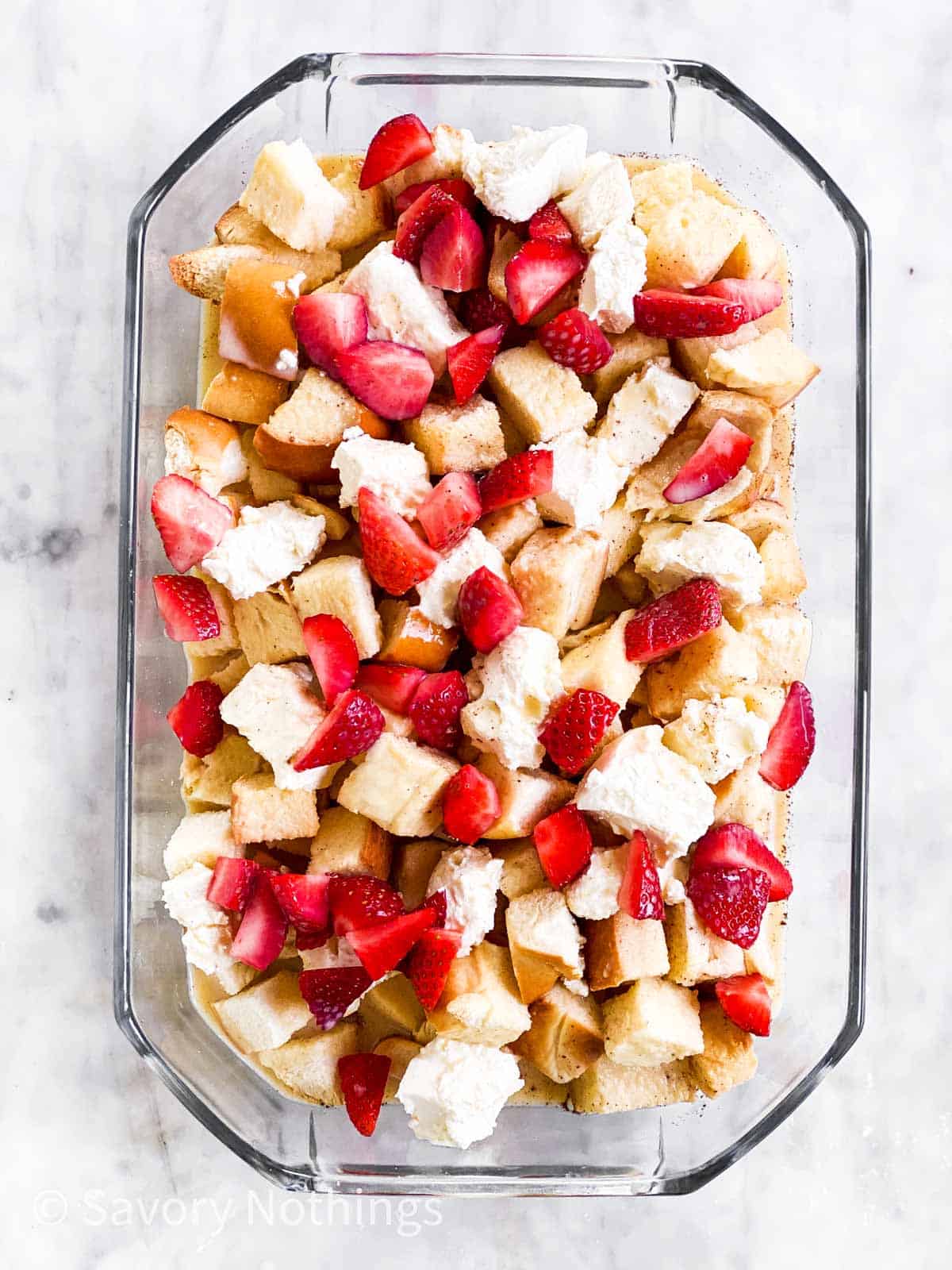 first layer of strawberry French toast casserole in glass dish sitting on marble surface