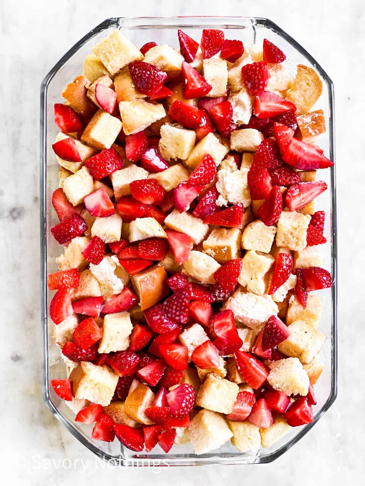 second layer of strawberry French toast casserole in glass dish sitting on marble surface