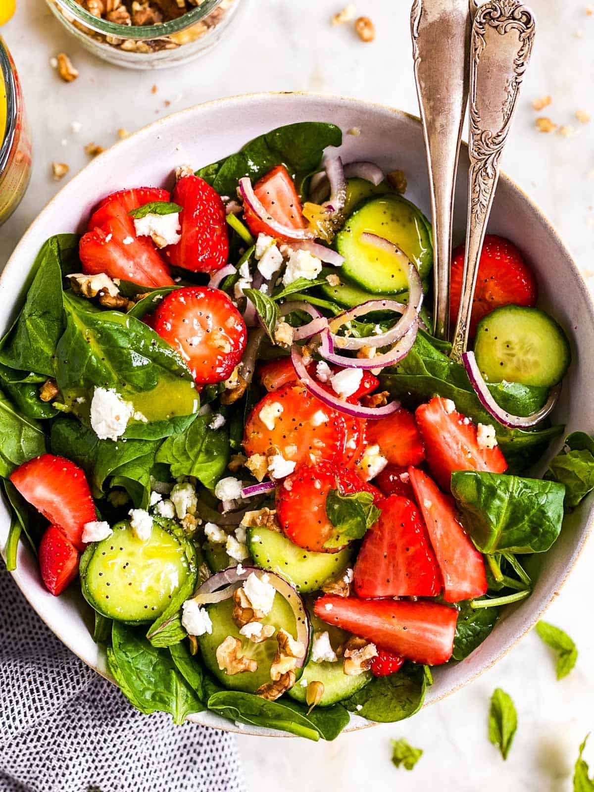 bowl with strawberry spinach salad and lemon poppy seed dressing in white salad bowl