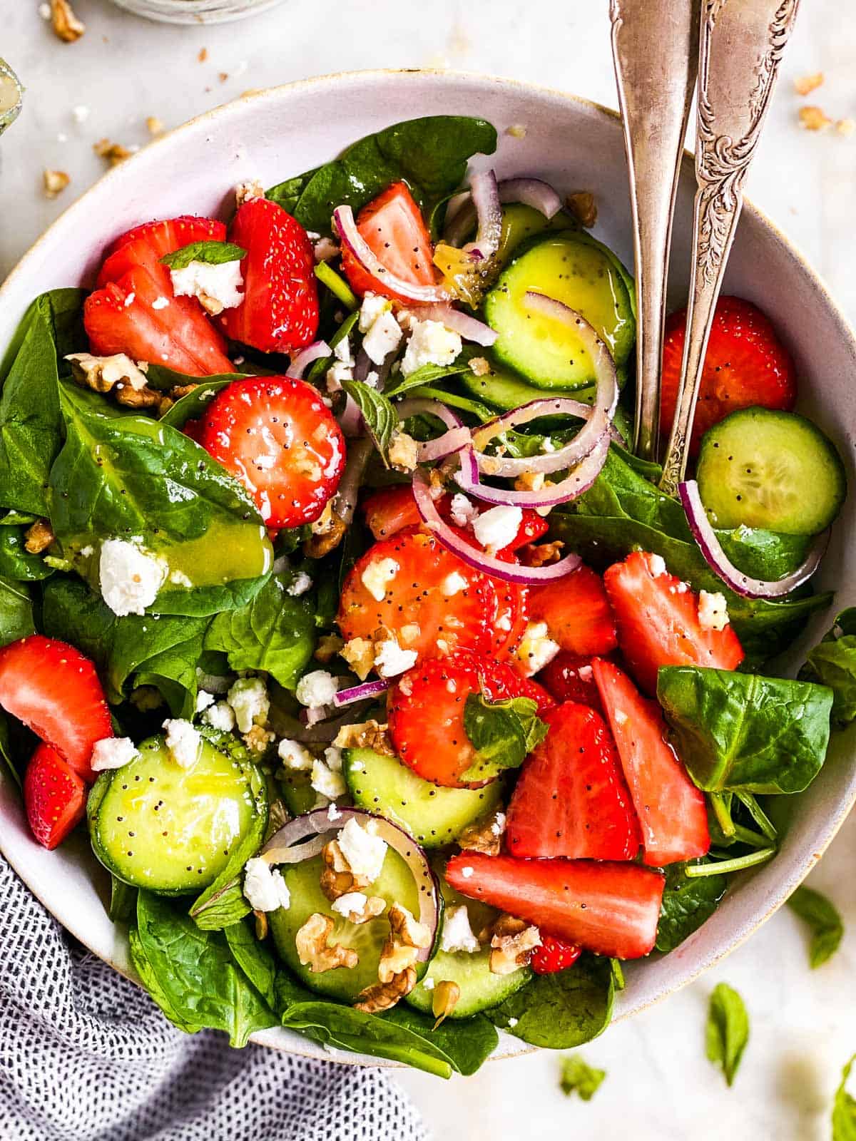 overhead close up view of white bowl with strawberry spinach salad