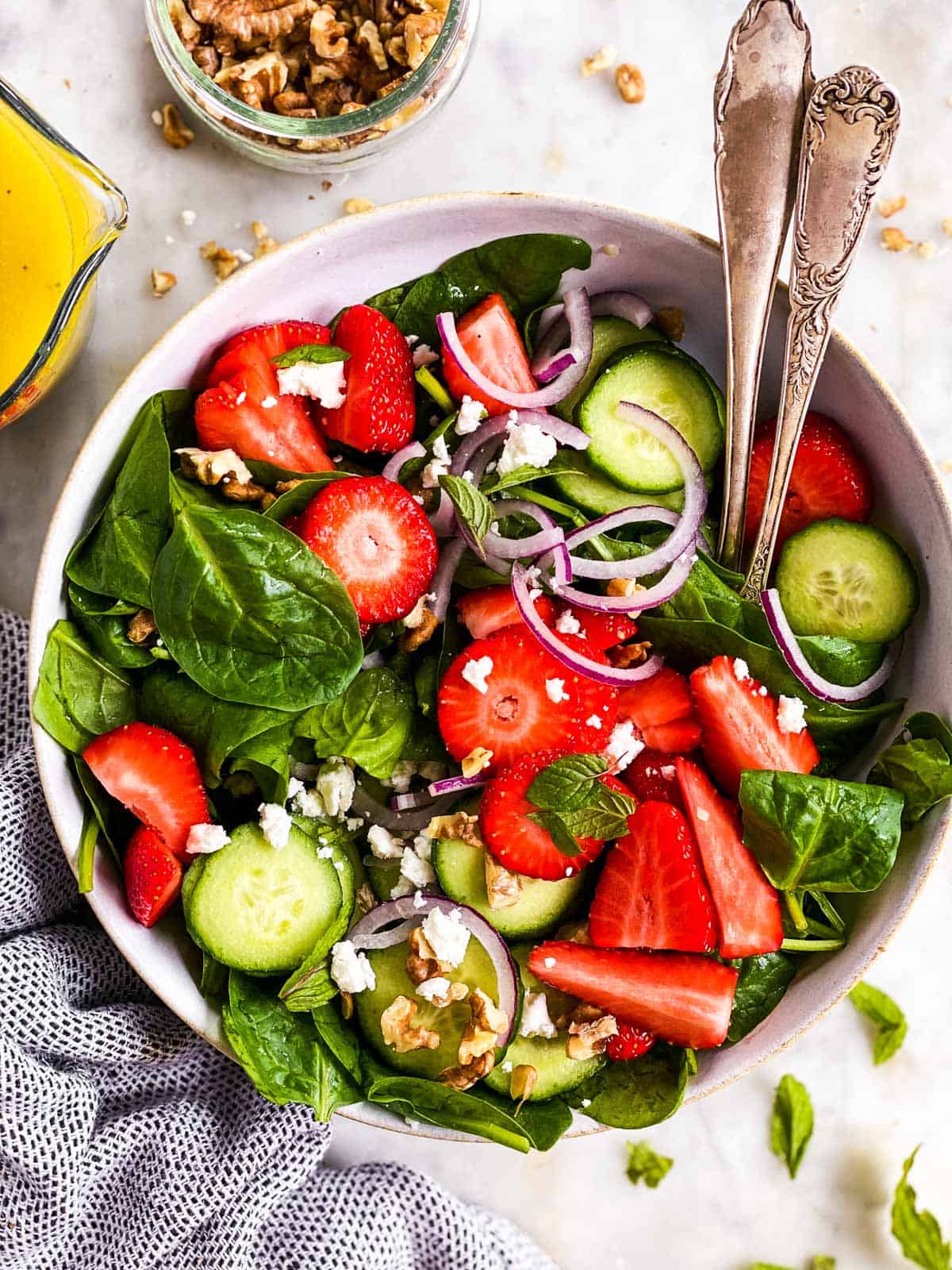 ingredients for strawberry spinach salad in white salad bowl