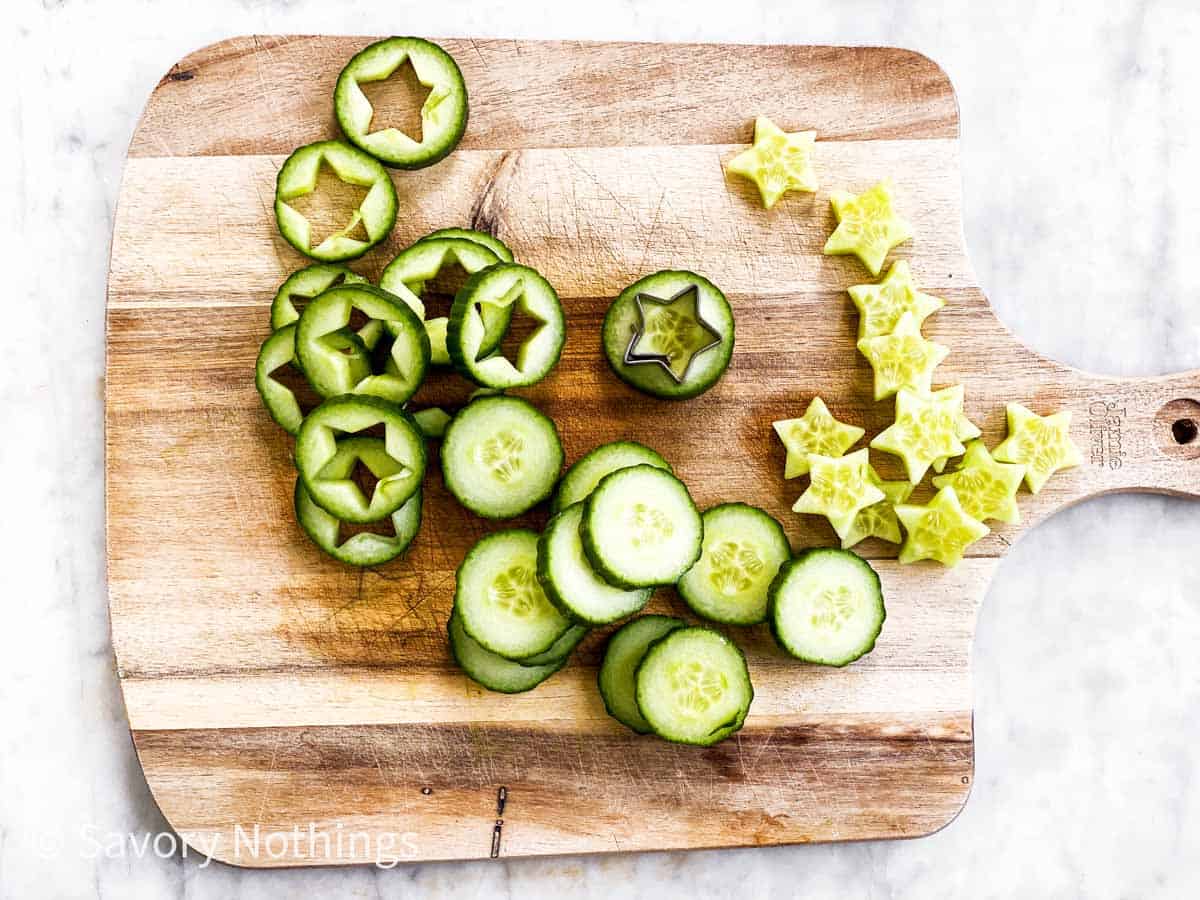 sliced cucumber with star cut outs on wooden chopping board