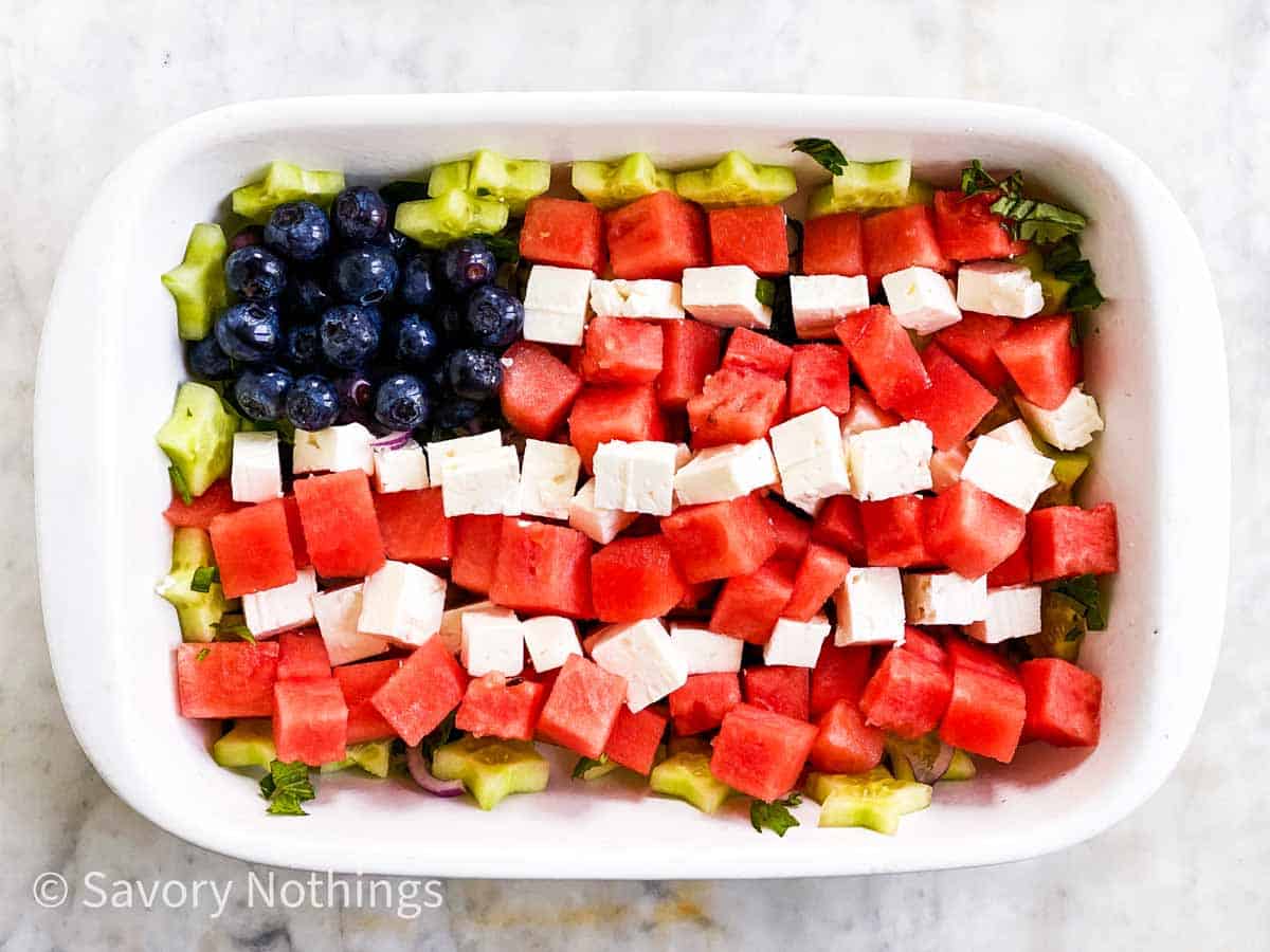 blueberries, feta cheese and watermelon cubes arranged as US flag in white rectangular dish