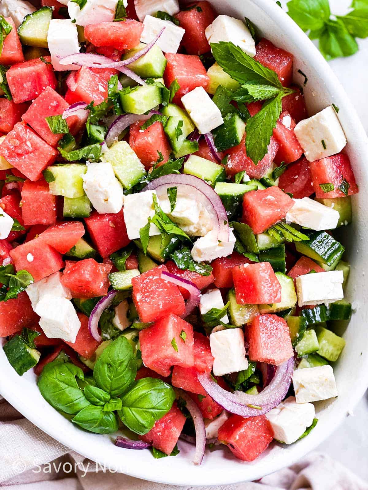 overhead close up of oval white dish with watermelon salad