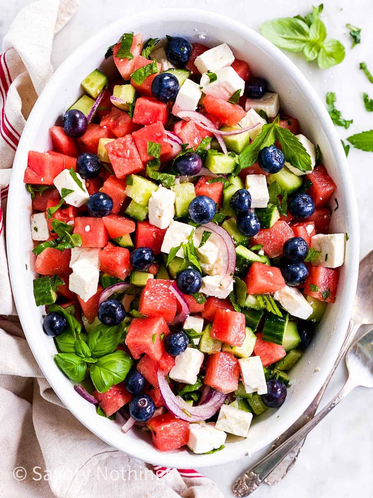 watermelon and feta salad with blueberries in white oval dish