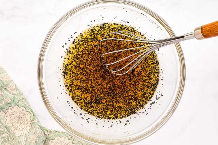 Poppy seed dressing for fruit salad in a glass bowl.
