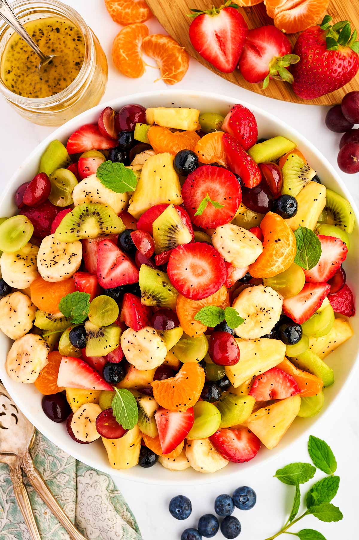 Bowl of fresh fruit salad surrounded by more fresh fruit.