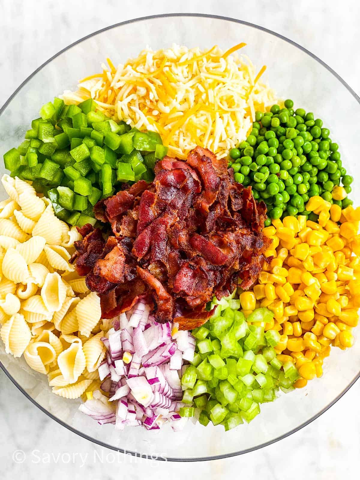 overhead view of ingredients for bacon ranch pasta salad in glass bowl