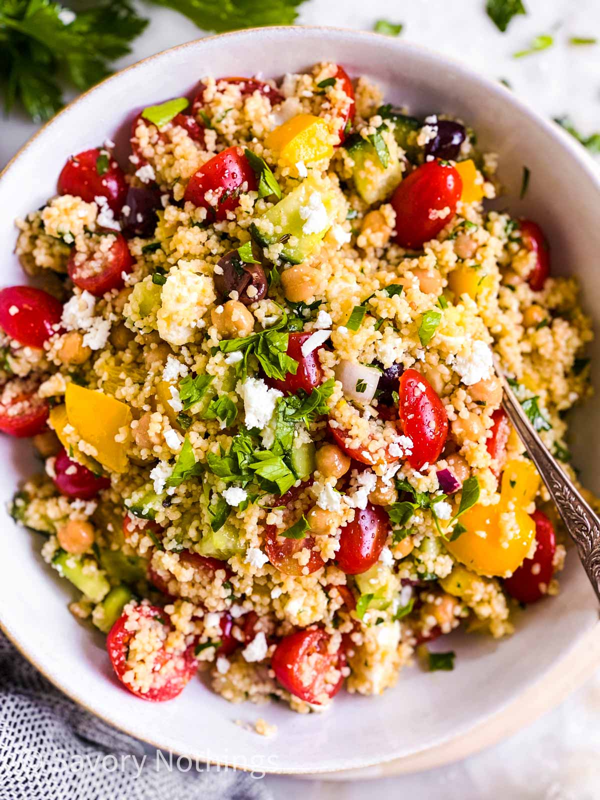 overhead view of couscous salad in white bowl with a fork