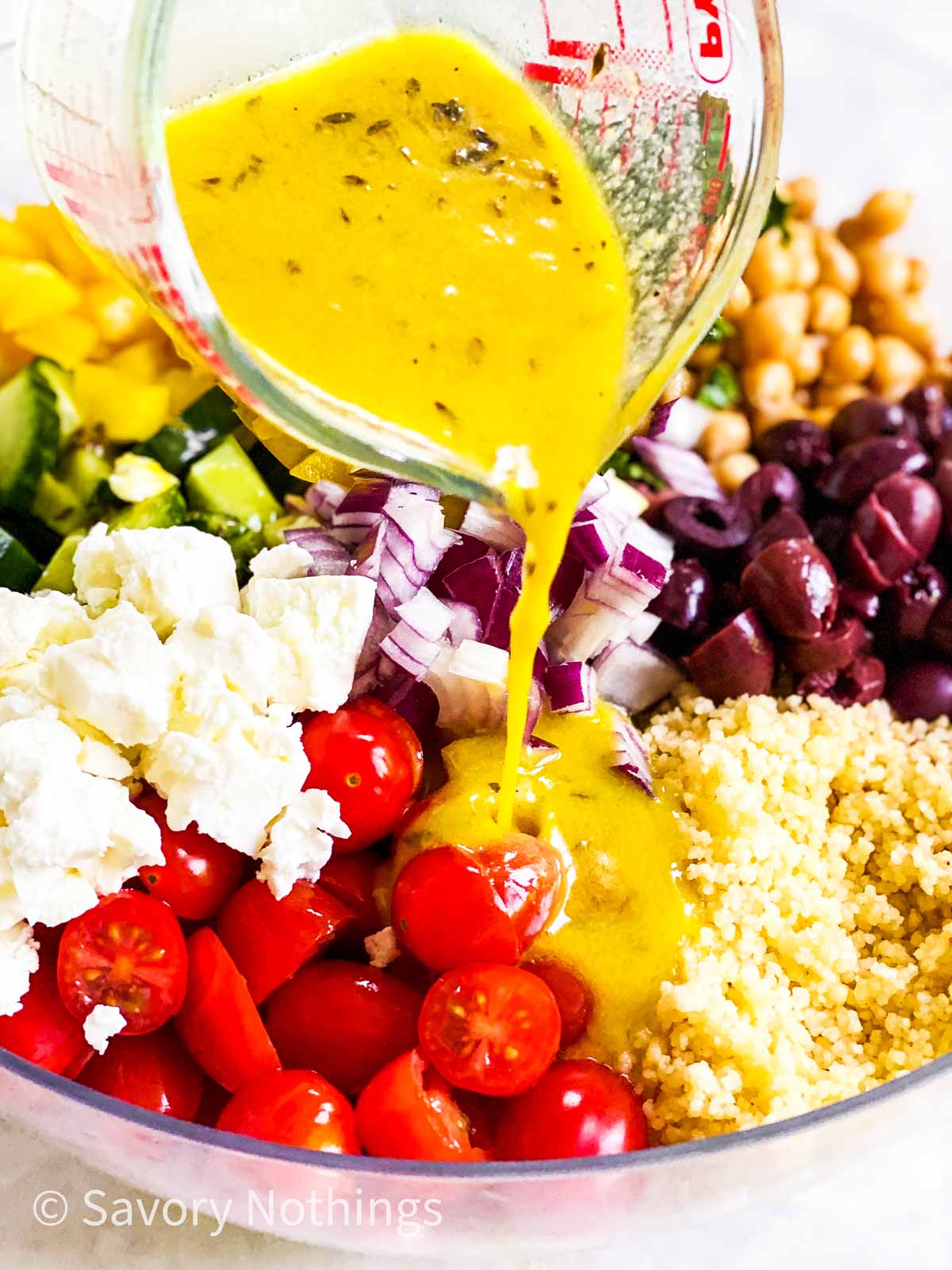 salad dressing pouring over couscous salad ingredients