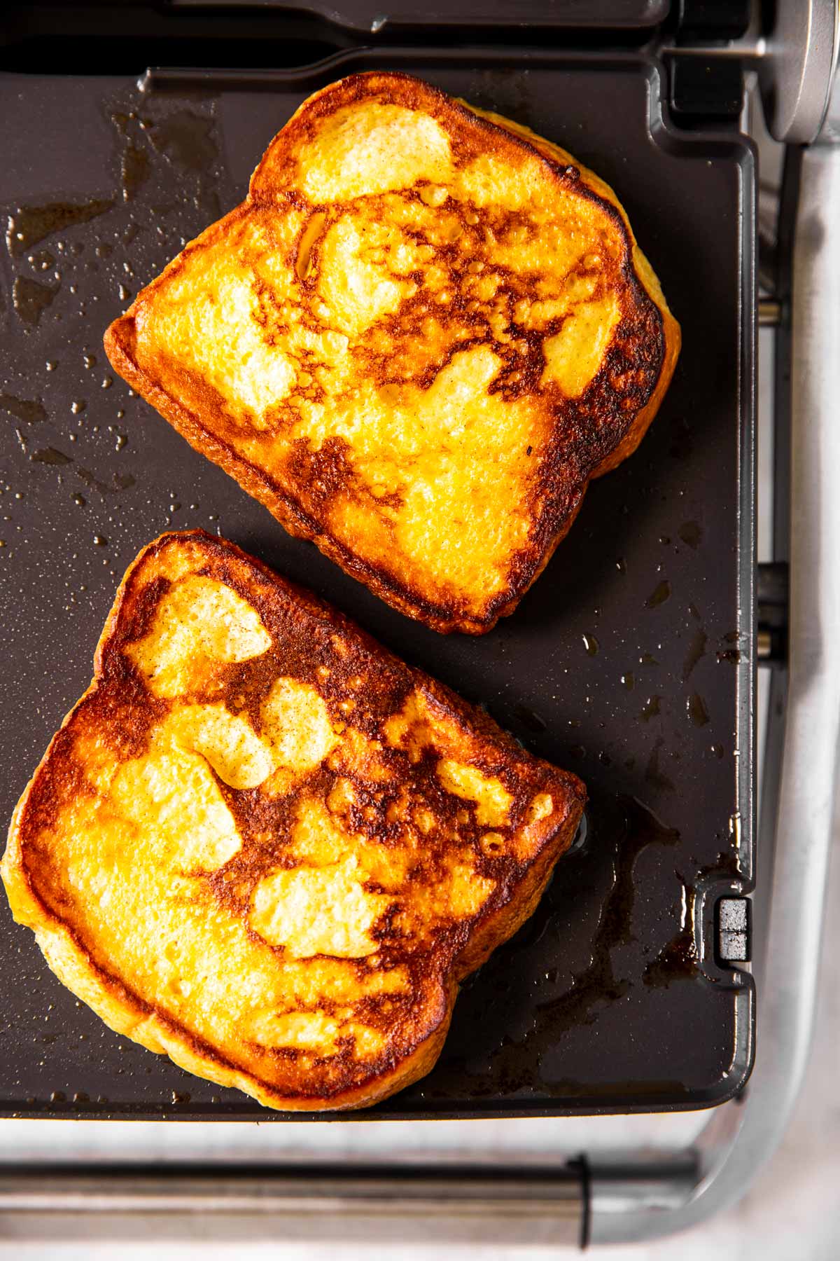 two pieces of cooked French toast on griddle