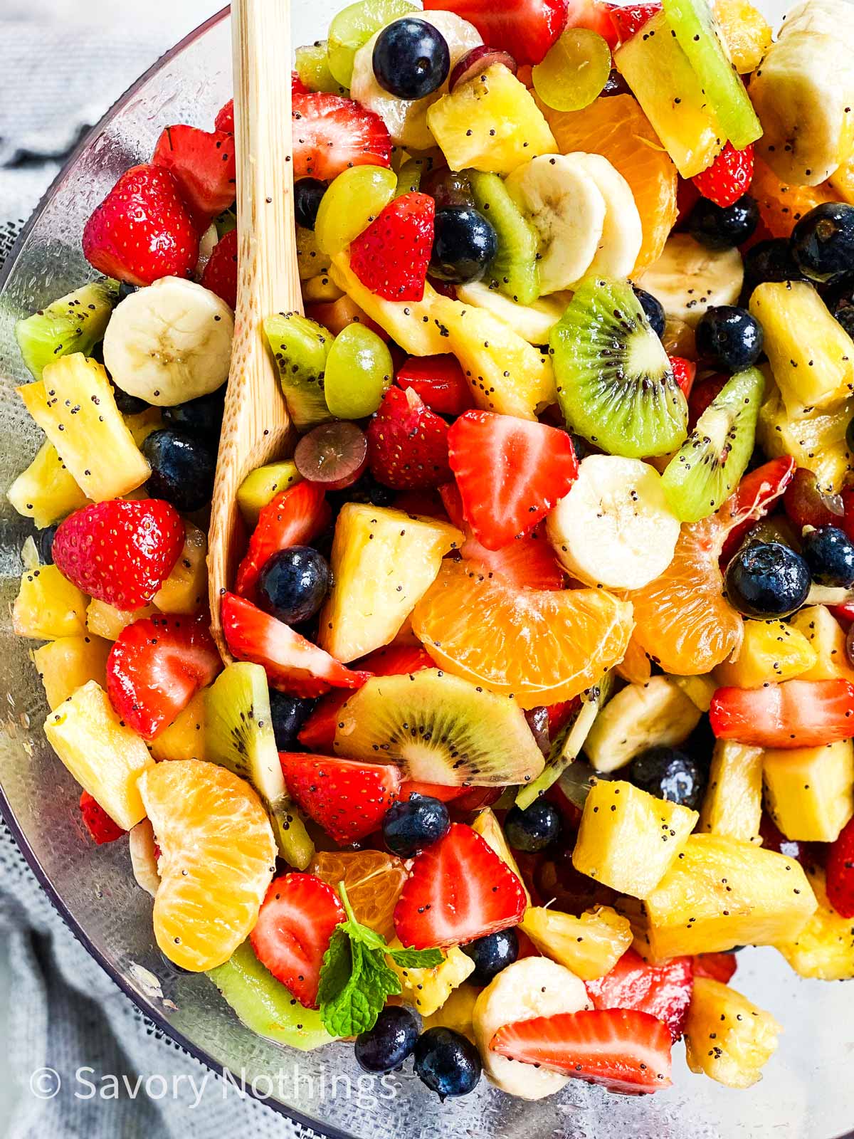 close up photo of wooden spoon in a bowl of fresh fruit salad