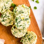 overhead view of sliced garlic herb butter on wooden board