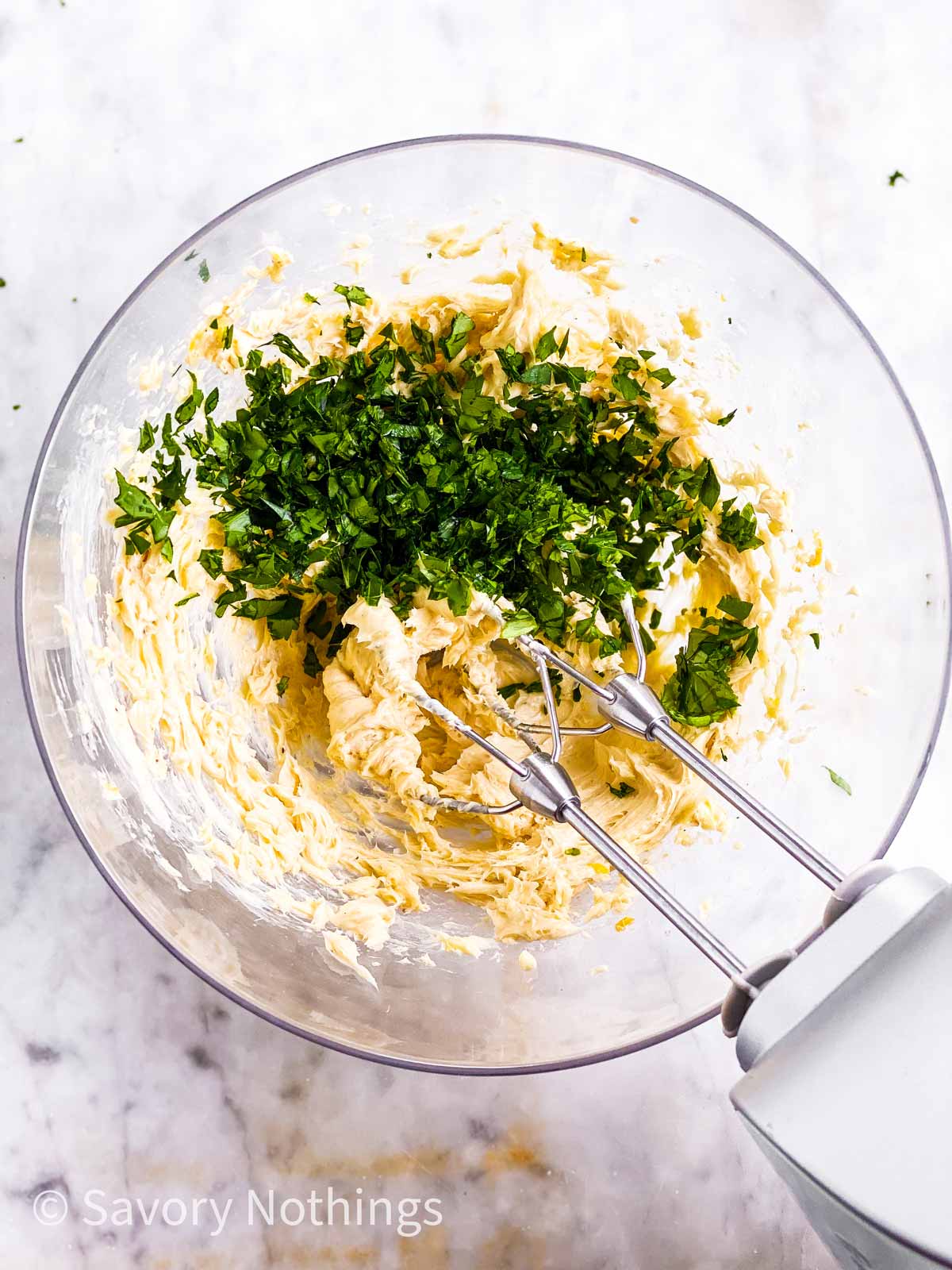 whipped garlic butter in glass bowl with fresh herbs