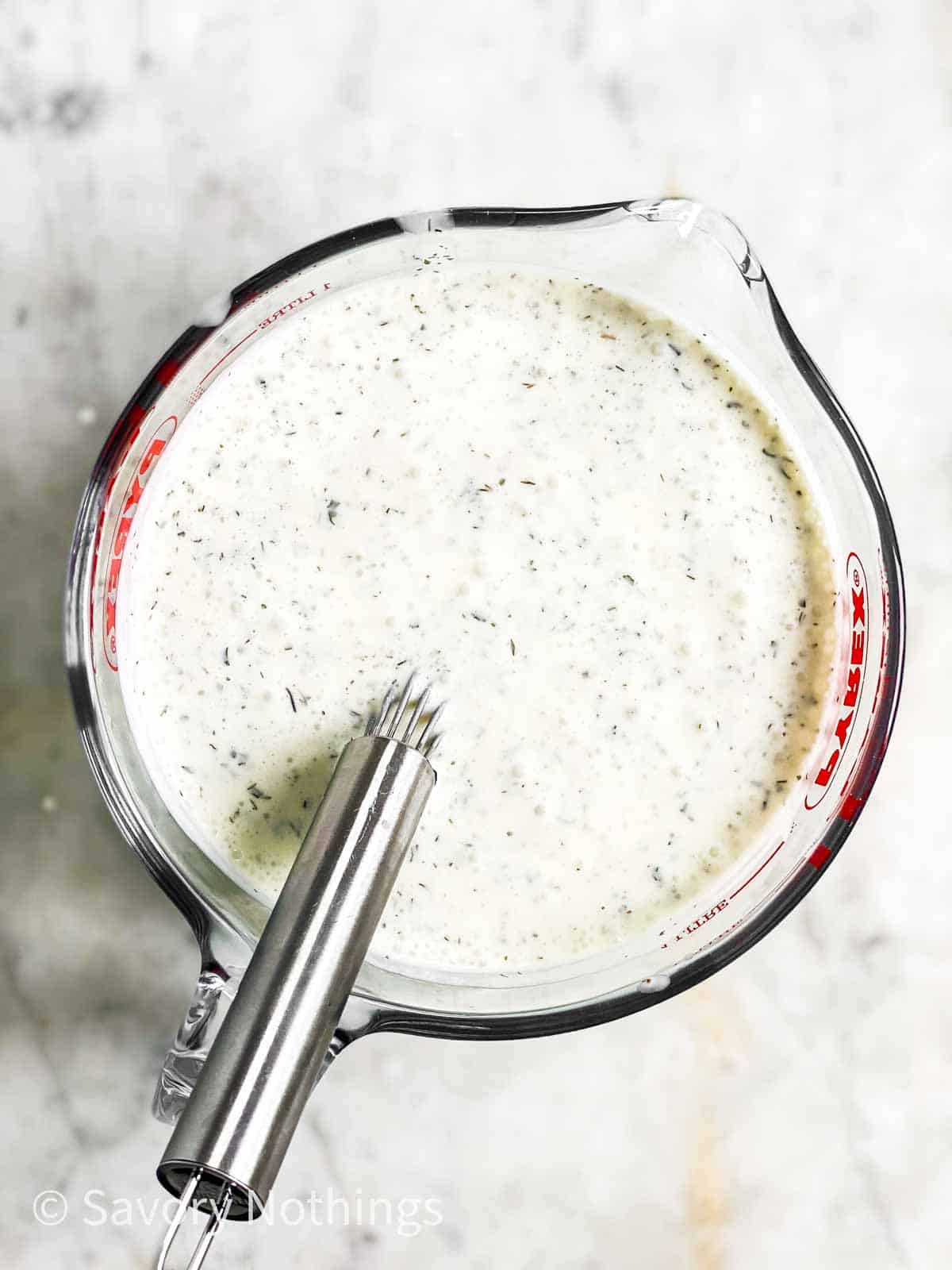 homemade ranch salad dressing in glass measuring jug with metal whisk