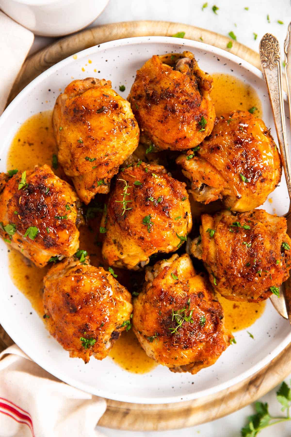 overhead view of eight chicken thighs on white plate with gravy