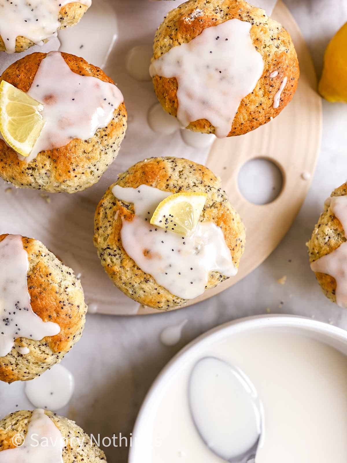 overhead view of glazed lemon poppy seed muffins garnished with sliced fresh lemon