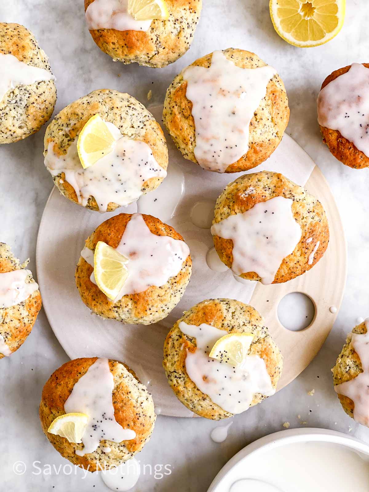 overhead view of several glazed lemon poppy seed muffins on marble and ceramic surface