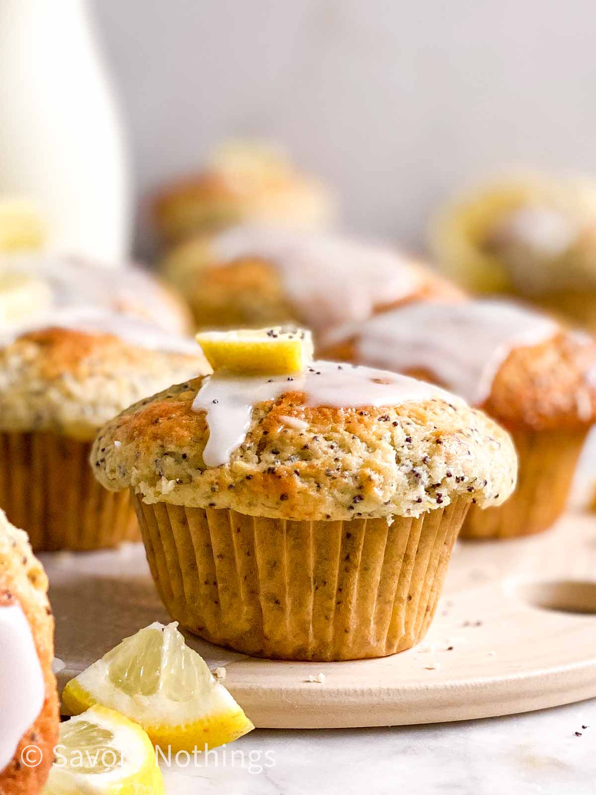 frontal view of glazed lemon poppy seed muffins in front of milk bottle